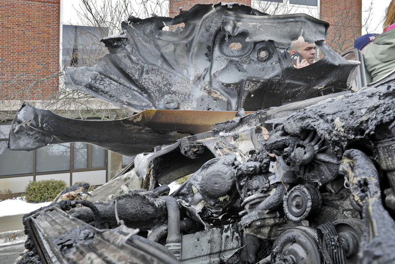 The owner of the vehicle that caught fire in front of St. Lukes hospital in New Bedford, MA, can be seen through a gap in the still smoldering engine compartment of his Mercedes.  PHOTO PETER PEREIRA