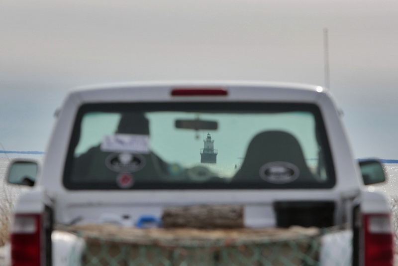 A man enjoys the view from Fort Phoenix in Fairhaven, MA as in the distance the iconic Butler Flats lighthouse peeks through the windshield of his truck.   PHOTO PETER PEREIRA