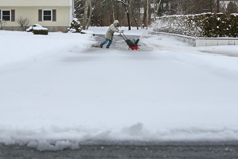 Joao Oliveira has his work cut out for him as he digs out his driveway at his home in Dartmouth, MA from the recent snowfall.  The heaviness of the snow forces Mr. Oliveira to run horizontal lines back and forth before reaching the street in the foreground. PHOTO PETER PEREIRA