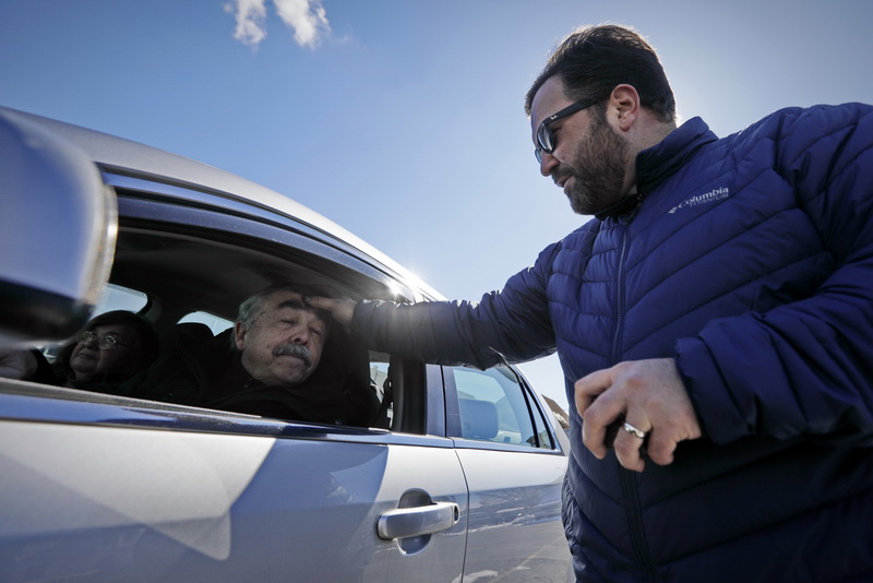 Rev. Scott Ciosek offers a prayer and ashes to Barry Starr and his wife Nancy Starr, along with any other motorists who drive up in the parking lot of the St. Martin's Episcopal Church on County Street in New Bedford, MA as part of his Ashes to Go program on ash Wednesday. PHOTO PETER PEREIRA