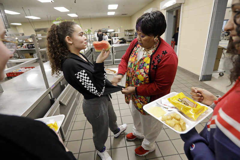 Maria Santos helps seventh grader Nevaeh DeMello, 12, clean her shirt after some watermelon juice fell on it during one of the six lunch periods at the Normandin Middle School in New Bedford, MA.  PHOTO PETER PEREIRA