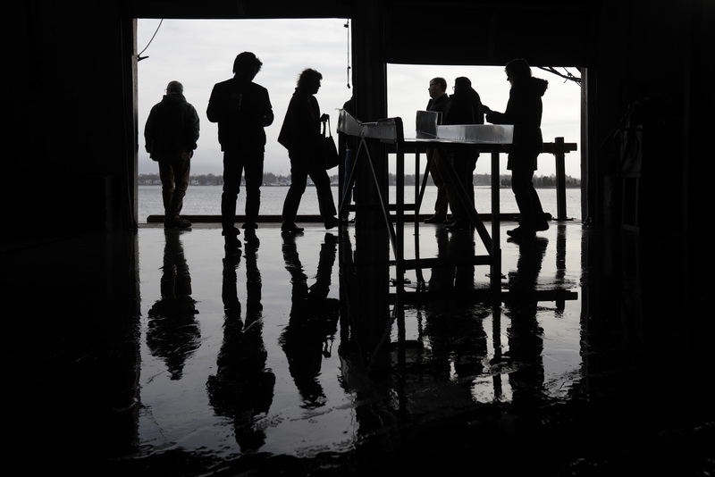 Seafood buyers from Asia, Europe, and the Middle East take in the view of the harbor from the boat unloading dock at the the BASE Seafood Auction house, during their visti to the area's leading seafood companies. 