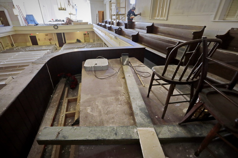 A very large cross which once stood on the altar, lies on the ground in the mezzanine, as Charles Hauck can be seen applying joint compound on the walls. PHOTO PETER PEREIRA