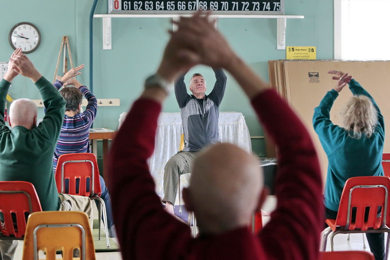 Instructor, Joey Machado, conducts a chair yoga session with seniors at the Haxelwood Senior Center in the south end of New Bedford, MA.  