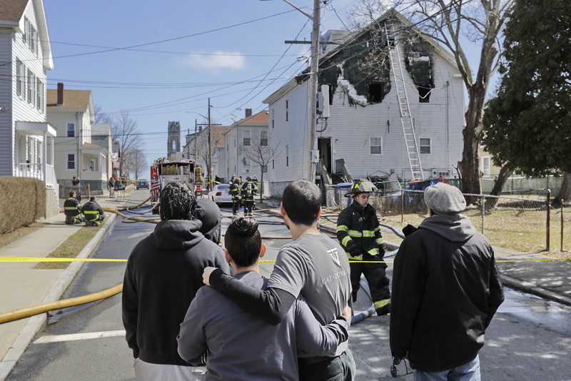 Branden Padilla, center, is given comfort by his cousin, as they watch New Bedford firefighters respond to a fire that broke out at Mr. Padilla's residence at 11 Spruce Street.  