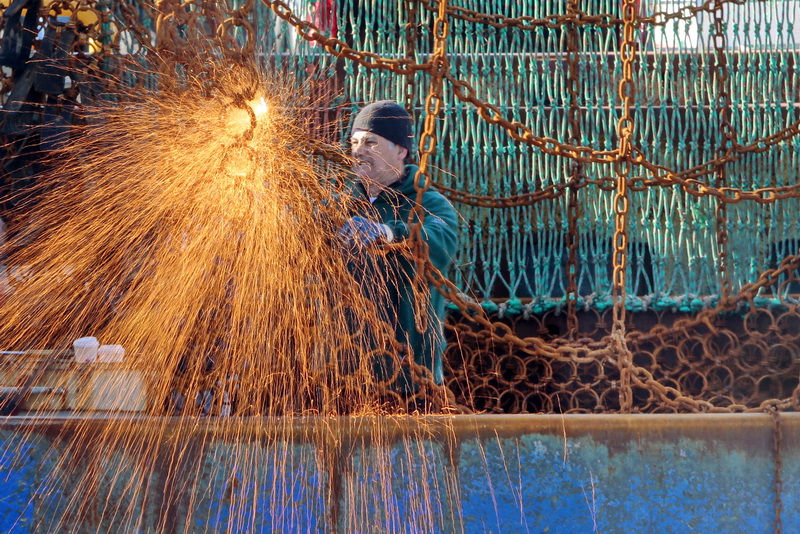 A fisherman sparks things up as he repairs the dredges aboard a scalloper docked in New Bedford, MA.    PHOTO PETER PEREIRA