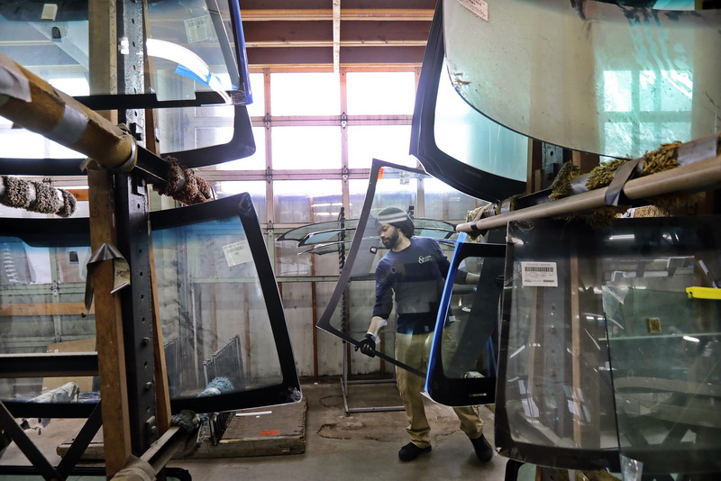 Steve Coelho walks past the huge inventory of glass, with a new windshield in hand for a repair he is performing at the Glaser Glass shop on Purchase Street in New Bedford, MA.    PHOTO PETER PEREIRA