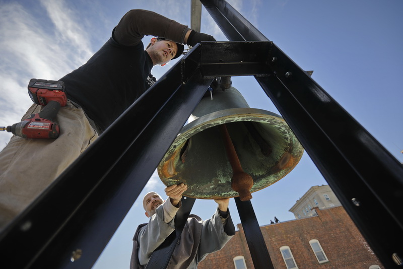 Friar John gives James Androuais of the Americlock company a hand, in installing a new steel bell frame and automation package on top of Our Lady's Chapel high above downtown New Bedford, MA  PHOTO PETER PEREIRA