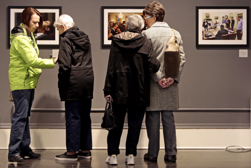 Donna Leary, left, helps her mother, Dorothy Yates with her nametag, as Dorothy Lowney speaks with her mother Doretta Lowney while looking at photos of President Obama taken by Pete Souza. Members of ALZ (Alzheimer's Association) who suffer from mild Alzheimer's and their family, take a closer look at photographs by Presidential photographer Pete Souza, while touring the New Bedford Art Museum as part of the ALZ Meet Up program.     PHOTO PETER PEREIRA