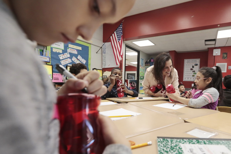 A student writes her name on her bottle, as Terry Wolkowicz, education director with the New Bedford Symphony Orchestra,  hands out some of reusable water bottles to third graders at the Hayden McFadden School in New Bedford, as part of a program by the New Bedford Symphony Orchestra in this year's Learning in Concert program entitled 