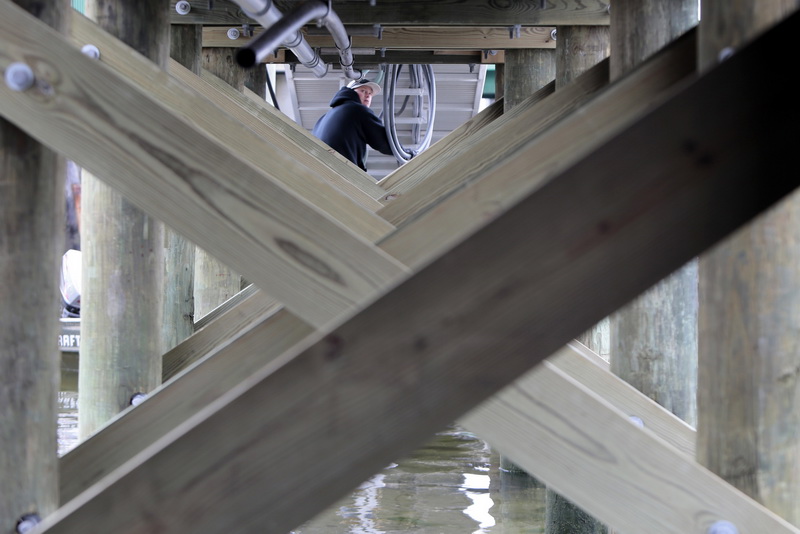 A worker installs the various electrical, drainage and various hardware that runs under the newly completed dock at the Maritime Center in Padanaram, MA.  PHOTO PETER PEREIRA