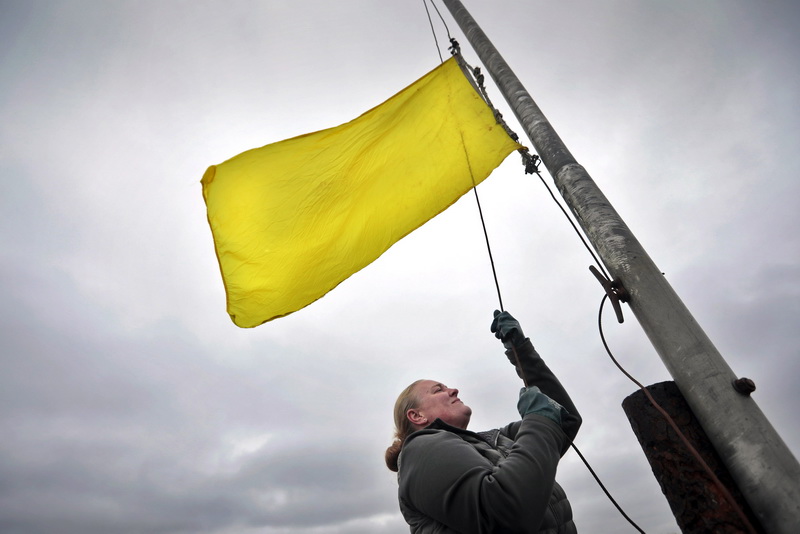 Under an ominous sky, Deputy Shellfish Warden, Megan Coito, hoists the yellow flag on East Rodney French Boulevard in the south end of New Bedford, MA, signifying that shell fishing in Clarkes Cove is permitted once again.  Because of constant rain, this is the first time this month that shell fishing has been permitted due to the 5 day grace period between the last heavy rainfall and when shellfishing is permitted once again.  PHOTO PETER PEREIRA