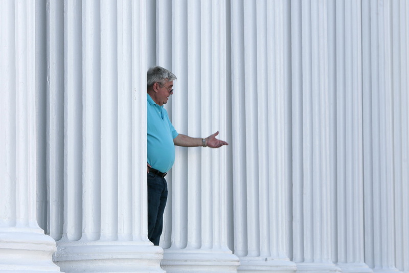 Mike DeBarros of J J Best Insurance is framed by the colonnade of the J J Best Banc  & Co. building on N. Water Street in downtown New Bedford, as he takes a customer call on his wireless headset. PHOTO PETER PEREIRA