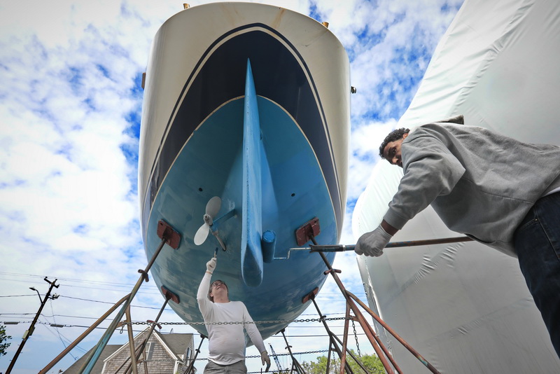 Jonathan Werbel and Gerald Wills of Fairhaven Yacht, give the bottom of a 36' sailboat a fresh coat of paint, as boating season starts ramping up across the region.  PHOTO PETER PEREIRA