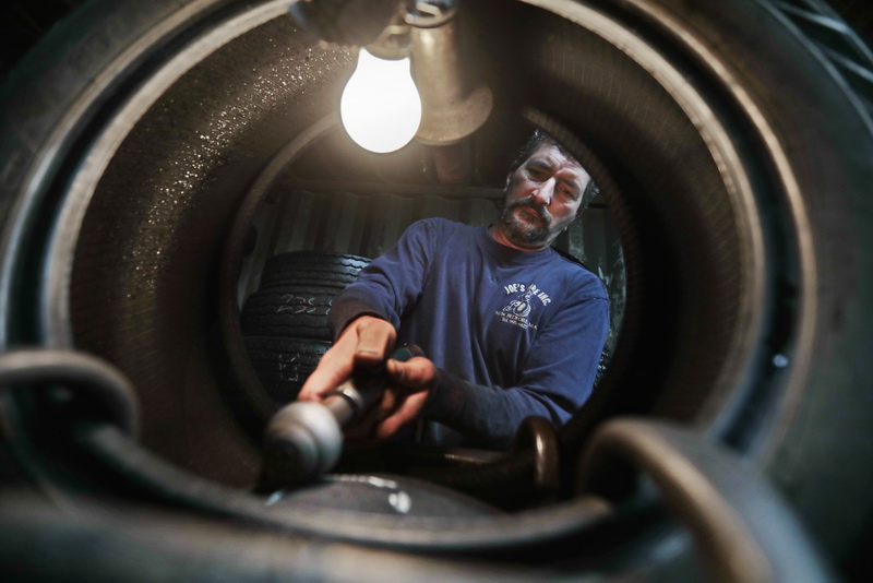 Russell Santos uses a rotary tool to scuff the area he has marked on the tire he is repairing at Joe's Tire on Acushnet Avenue in the north end of New Bedford, MA.  PHOTO PETER PEREIRA