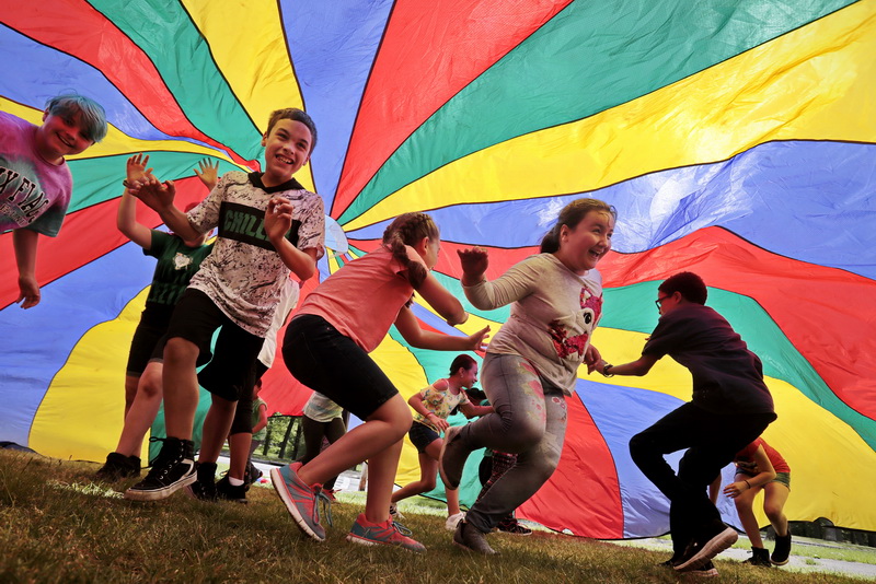 Charles Ashley Elementary School fourth graders have a great time running under a colorful parachute, during Field Day outside their school in the north end of New Bedford, MA. PHOTO PETER PEREIRA