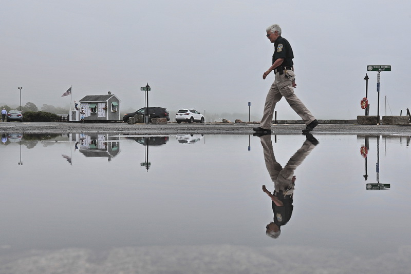 Mattapoisett harbormaster Jill Simmons seemingly walks on water, as she makes her way across the Freddie Brownell Wharf in Mattapoisett, MA past a large puddle of water from the heavy overnight rains.     PHOTO PETER PEREIRA