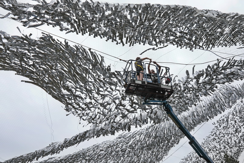 CLead fabricator Derek Welsh and assistant, Tess Oldfield tie two of the sections of the Silver Current art installation hanging over Custom House Squre in downtown New Bedford, MA.  Silver Current is part of a project by artist Patrick Shearn and his company, Poetic Kinetics, entitiled Summer Winds  PHOTO PETER PEREIRA