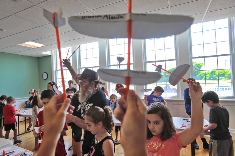 Ed the Wizard has attendees hold up their plane to check on how the group is proceeding during his Rocket and Airplane Building Workshop held at the Acushnet Public Library as part of a grant from the Acushnet Cultural Council. PHOTO PETER PEREIRA