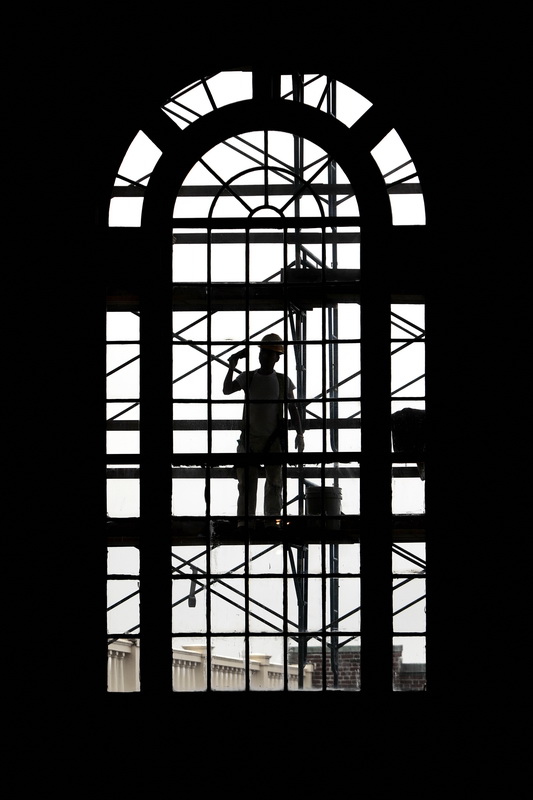 Darwin Lopez paints the mullions between glass panes on the iconic extra large windows of the Lagoda room at the Whaling Musem in New Bedford as part of extensive exterior restoration. 