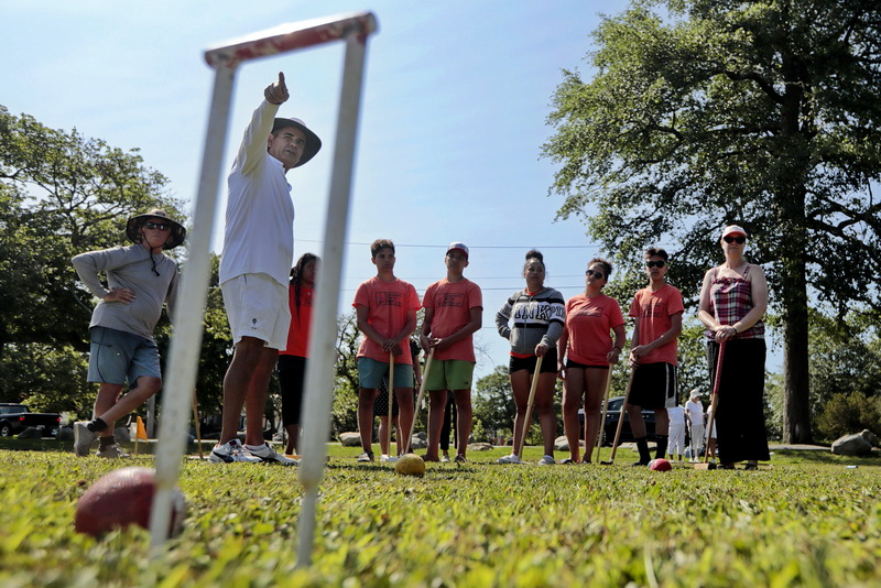 International and American Croquet Champion Sherif Abdelwahab, is seen through a wicket, as he explains the rules of croquet to participants from the Community Boating Center during a demonstration of the sport at Hazelwood Park in the south end of New Bedford, MA.   PHOTO PETER PEREIRA