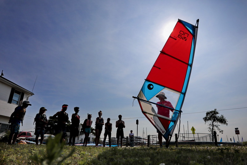 Participants look on as windsurfing instructor Jim DeSilva explains how to steer a windsurfer during the new Community Boating Center windsurfing program held in Clarks Cove in the south end of New Bedford, MA.   PHOTO PETER PEREIRA