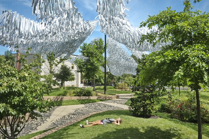 Yolanda Cavicchio lies down and enjoys the sounds of the Silver Current art installation hanging over Custom House Square in downtown New Bedford, MA.  PHOTO PETER PEREIRA