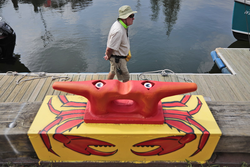 Port of New Bedford launch driver, Bob Clarkson, walks past a cleat on the dock painted into a crab in front of the visitors center on Fisherman's Wharf in New Bedford, MA.  PHOTO PETER PEREIRA