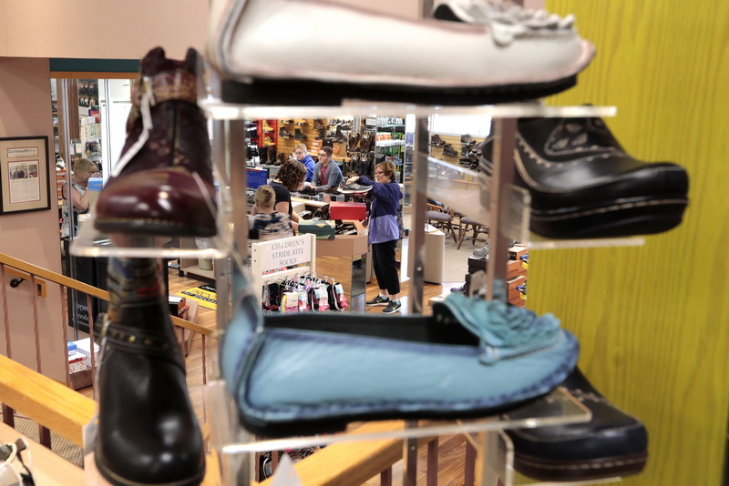 Sheridan Medeiros buys a new pair of 'going back to school' sneakers for her grandchildren Mason and Maxwell as seen through a display of shoes on sale at the Harve's Shoe Box.   Harve's Shoe Box on State Road in Dartmouth, MA is celebrating its 70th anniversary.   PHOTO PETER PEREIRA