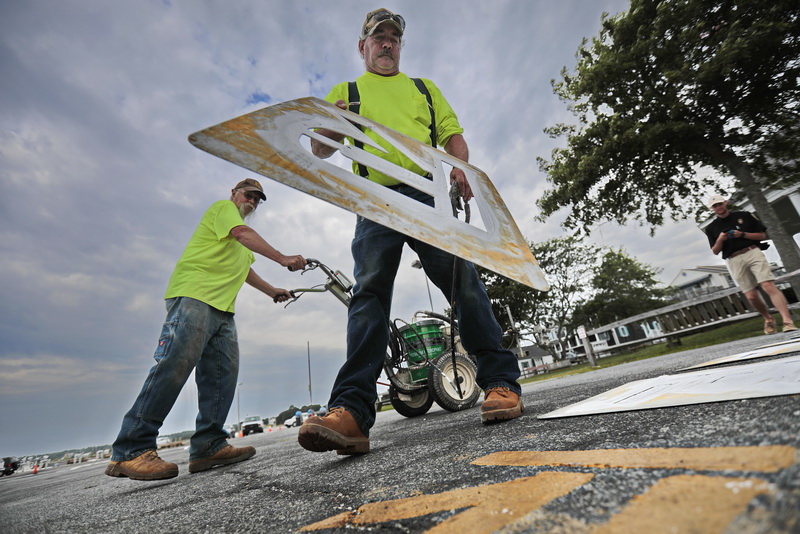 Mattapoisett Highway Department's Rocky Fleurent and Jay Dupont use stencils to change the color of the lines and letteri on the wharf in Mattapoisett, MA from yellow to white as part of a state mandate.   PHOTO PETER PEREIRA