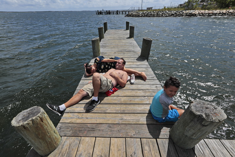 Joel Brown his girlfriend Meredith Winn and her son Christian Winn, 7, enjoy a perfect afternoon on a pier in the south end of New Bedford, MA.   PHOTO PETER PEREIRA