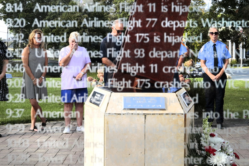 As A woman wipes a tear from her cheek, as seen through a pane of glass etched with the events of September 11, 2001, during a ceremony held at the 9/11 memorial in front of the Acushnet Fire Station at the intersection of Main Street and Russell Street in Acushnet.  A beam from the World Trade Center can be seen in the center of the photo  PHOTO PETER PEREIRA