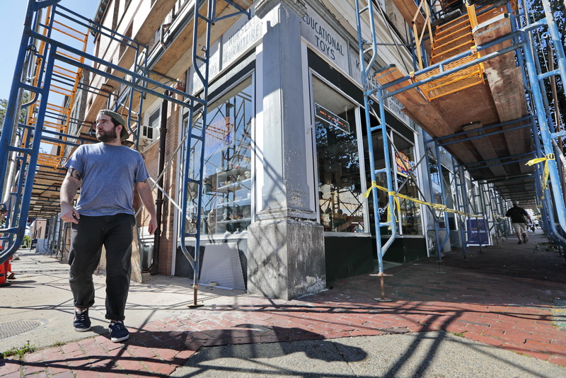 Two pedestrians in different directions, under the staging of the building being repairied at the intersection of Union Street and 6th Street, in downtown New Bedford, MA.  PHOTO PETER PEREIRA