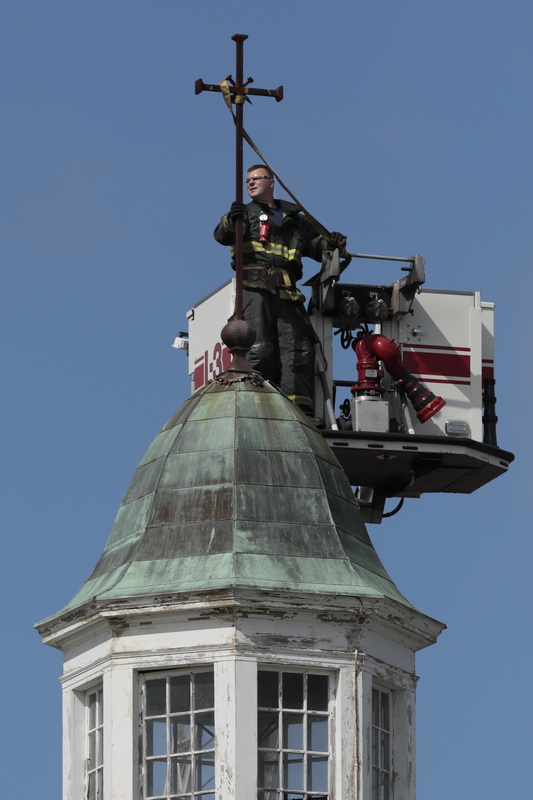 New Bedford firefighter Michael Cabral, works on removing the cross from the top of the Saint Anne church's steeple, before it is demolished laters this week to make way for a Public Safety Center. 