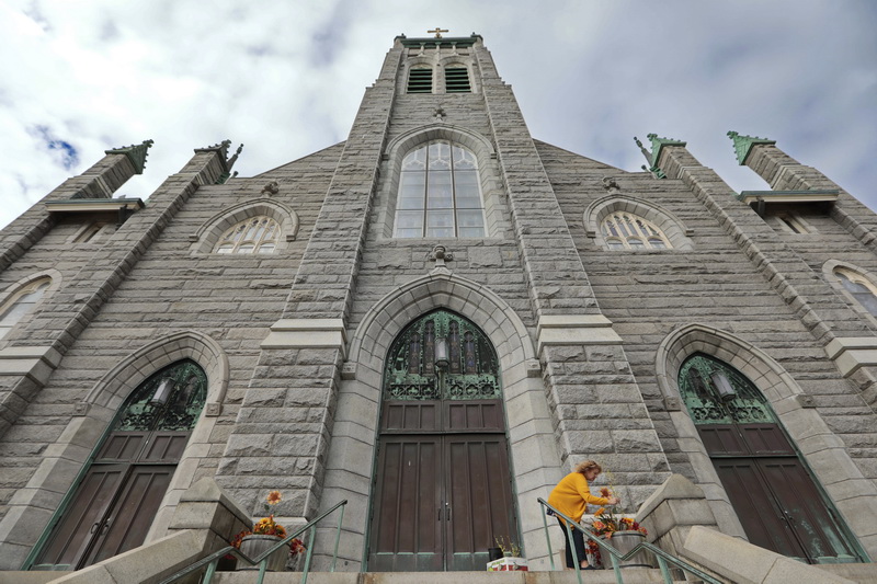 Jane Paul volunteers her time to add a touch of autumn to the front of Our Lady of Guadalupe Parish at St. James Church on County Street in New Bedford, MA. PHOTO PETER PEREIRA