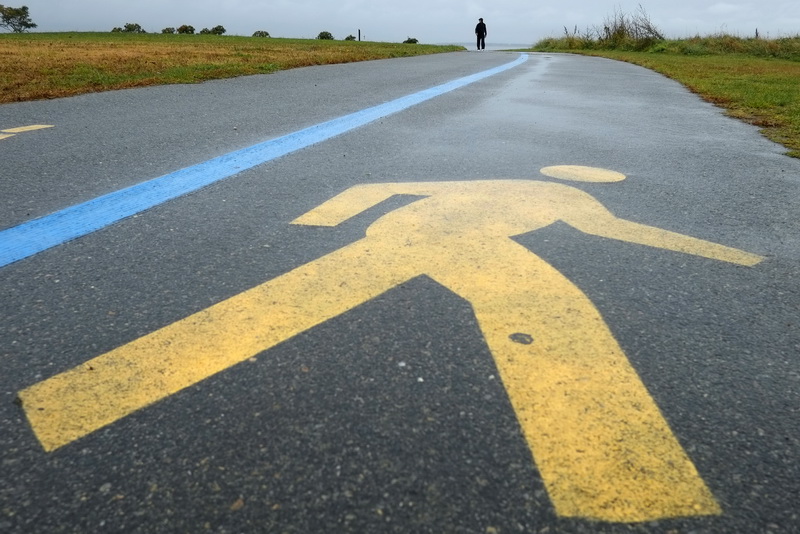 A man goes for a walk on the walking path around the beaches in the south end of New Bedord on a rainy morning. 