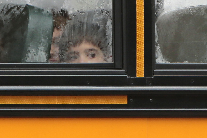 Moisture runs down the window of a bus as a student heading to school, looks out on another rainy morning in New Bedford, MA. 