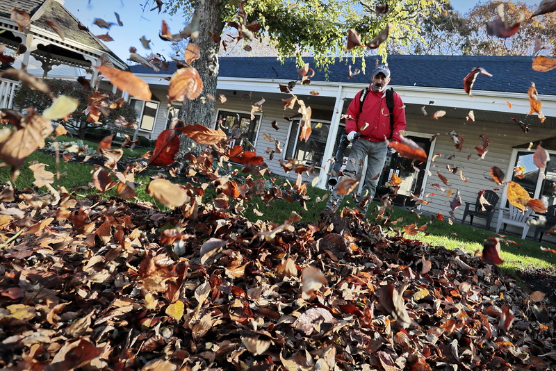 Joe Souza uses a leaf blower to wrangle up the leaves in front of the Courtyard Restaurant in Fairhaven, MA.