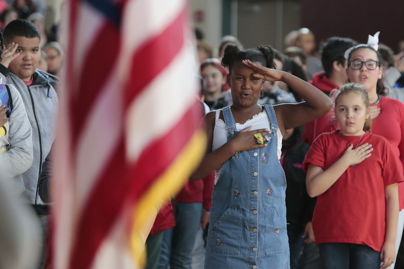 Students salute the flag during the playing of the National Anthem during the annual Veteran's Day ceremony held at the Roosevelt Middle School in the south end of New Bedford.   