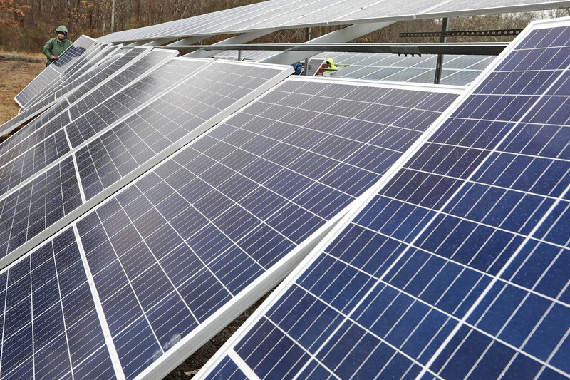 Miquel Lopes and fellow JR Electric workers install solar panels at a new solar farm being built in a lot behind the Tifereth Israel Congregation Synagogue on Brownell Avenue in New Bedford, MA on a rainy day.