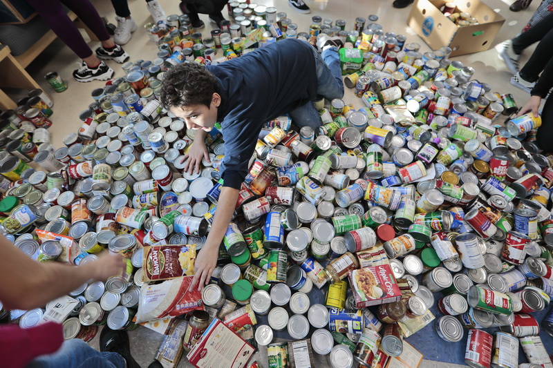 Eighth grader Nikolas Santiago, 14, reaches for a bag of rice to hand to his classmate, as he and fellow Normandin Middle School students sort and prepare food baskets to give to the needy for Thanksgiving, with cans they collected throughout the school year.  The collected over 3000 cans.