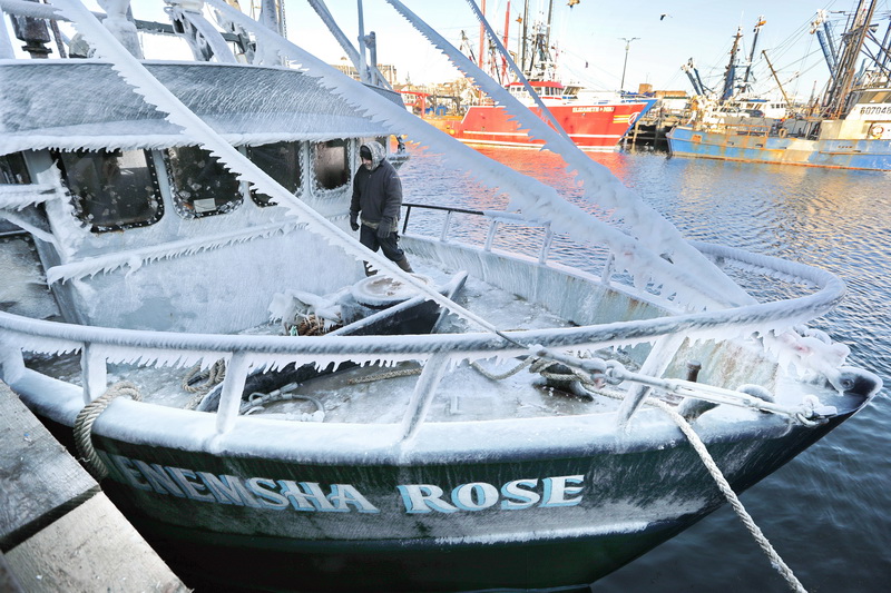 After arriving in New Bedford, MA, captain Mike Oliveira, walks across the frozen bow of the Menemsha Rose crab boat, in preparation to unload it's catch at Liberty Lobster in New Bedford, MA on a frigid morning.  PHOTO PETER PEREIRA