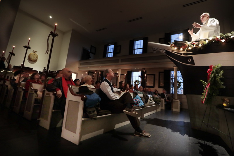 Candles provide the only light, as parishioners look as Pastor Paul Wheeler of the Trinity Lutheran Church. conducts the annual Christmas Candlelight Service from the iconic pulpit inside of the historic Seamen's Bethel in New Bedford, MA.  PHOTO PETER PEREIRA