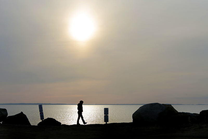 A woman goes for an early morning walk around Ned's Point in Mattapoisett, MA as the sun rises in the distance.  PHOTO PETER PEREIRA