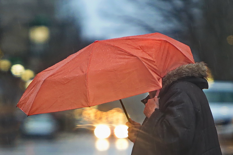 A woman holds on to the strap of her umbrella as she makes her way down Elm Street on a rainy morning in downtown New Bedford, MA.  PHOTO PETER PEREIRA