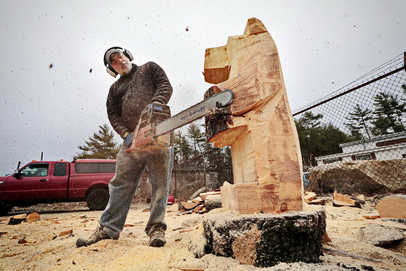 Christian Smith of Living Timber Chainsaw Carvings sends wood chips flying as he carves a bear from a tree trunk at his work area on Route 6 in Dartmouth, MA.  PHOTO PETER PEREIRA