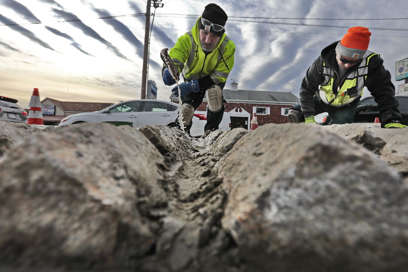 Joe Conde uses a brush with water to help the cement adhere to the cobbles, as Michael Barboza places cement between the Belgian stones they just installed on their sides at the intersection of Route 140 and Route 6.  The stones are placed this way in the hope of keeping panhandlers from standing on the median.  PHOTO PETER PEREIRA