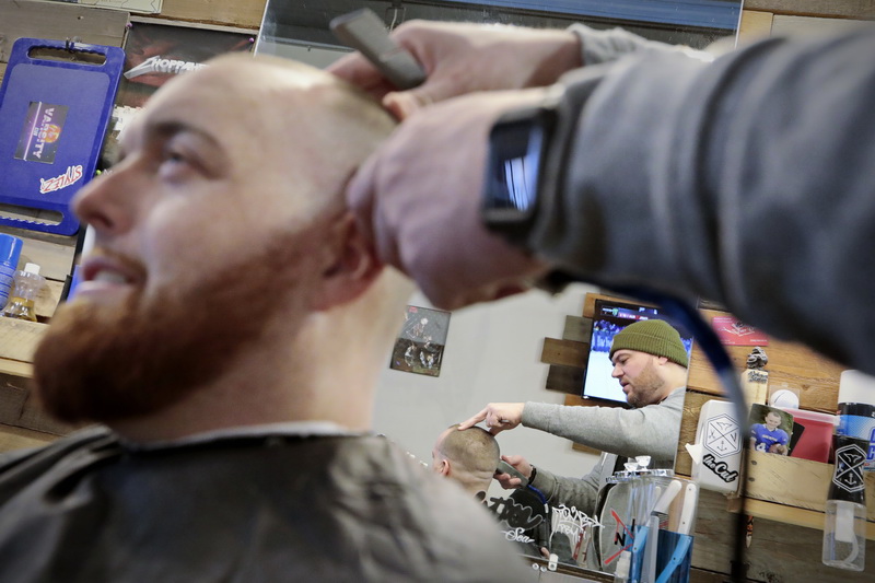 Jeff St.Pierre, owner of the New Bedford Barber Co. on William Street, is reflected on the mirror beyond as he gives Phelan Dussault a hair cut at his barber shop in downtown New Bedford, MA.   PHOTO PETER PEREIRA