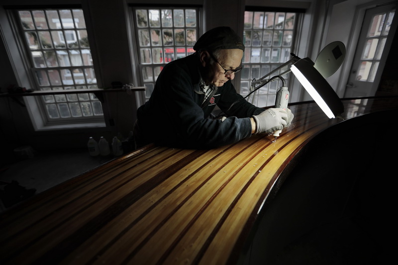 Chuck Rooney uses a rotary tool and a dentist light, to find and drill out any imperfections on the first layer of epoxy resin he laid on the bar he made for Cultivator Shoals marini bar on Union Street in New Bedford, MA, before applying the final coat of resin.  PHOTO PETER PEREIRA