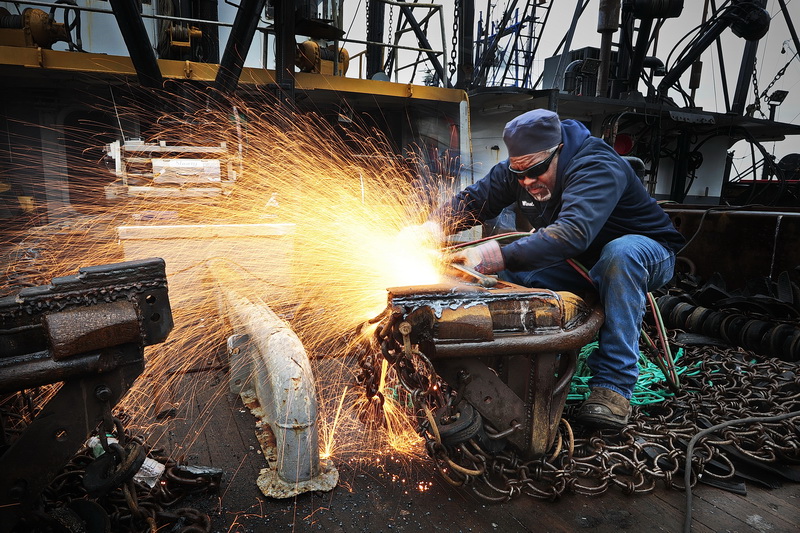 Ray Winston of Blue Fleet Welding, sends sparks flying while using a cutting torch to make modifications to the dredges aboard the scalloper Predator docked in New Bedford, MA.  PHOTO PETER PEREIRA